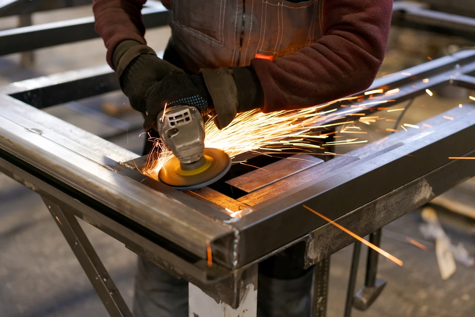 Atelier industriel intérieur avec opérateur manipulant une scie à ruban métallique en fonctionnement